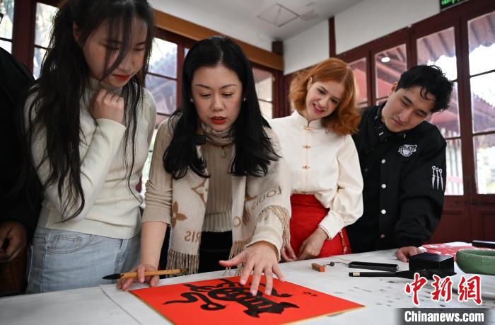 1月20日，西泠印社社員李硯（左二）為外籍留學(xué)生講述蛇年福字貼創(chuàng)作靈感。當(dāng)日，來自巴西、馬來西亞、加納、哈薩克斯坦的外籍留學(xué)生在浙江杭州西泠印社體驗(yàn)福貼、春聯(lián)和篆刻，感受古老的中國傳統(tǒng)文化。中新社記者 王剛 攝