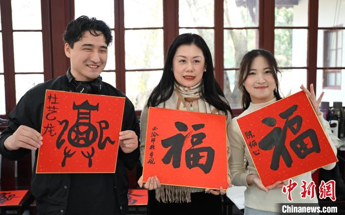1月20日，外籍留學(xué)生和西泠印社社員李硯(中)展示各自創(chuàng)作的福貼。當(dāng)日，來自巴西、馬來西亞、加納、哈薩克斯坦的外籍留學(xué)生在浙江杭州西泠印社體驗(yàn)福貼、春聯(lián)和篆刻，感受古老的中國傳統(tǒng)文化。中新社記者 王剛 攝
