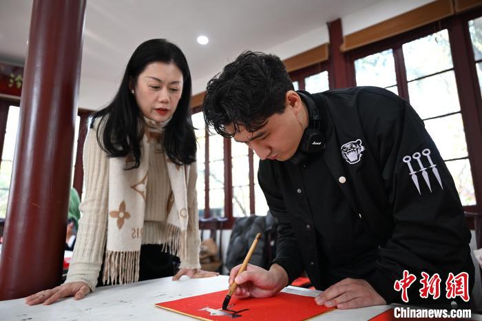 1月20日，外籍留學(xué)生在西泠印社社員李硯指導(dǎo)下寫福。當(dāng)日，來自巴西、馬來西亞、加納、哈薩克斯坦的外籍留學(xué)生在浙江杭州西泠印社體驗(yàn)福貼、春聯(lián)和篆刻，感受古老的中國傳統(tǒng)文化。中新社記者 王剛 攝
