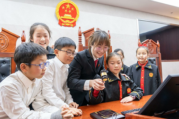 圖①：干警帶同學(xué)們體驗(yàn)敲法槌。