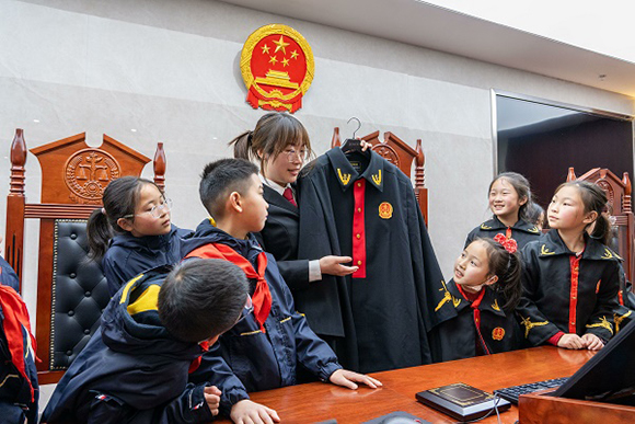 圖②：干警向同學(xué)們介紹法袍。